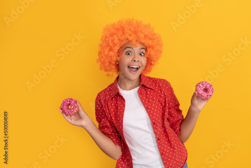 surprised kid in fancy orange wig hair hold sweet glazed donut, surprise