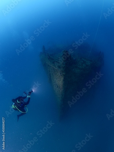 scuba divers exploring old ship wreck with torch light underwater from 1 world war ww1 wreck ocean scenery of history