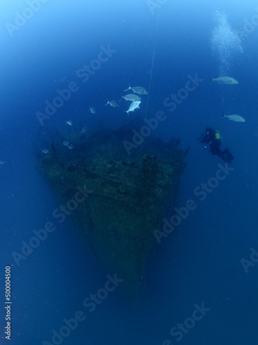 scuba divers exploring old ship wreck with torch light underwater from 1 world war ww1 wreck ocean scenery of history