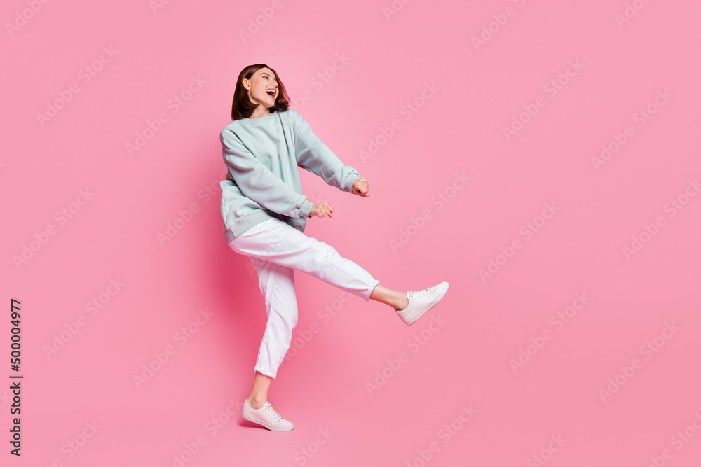 Full body profile side photo of youth cheerful girl have fun dancing look empty space isolated over pink color background Full body profile side photo of youth cheerful girl have fun dancing look empty space isolated over pink color background