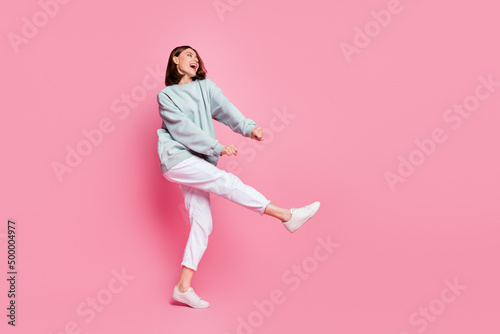 Full body profile side photo of youth cheerful girl have fun dancing look empty space isolated over pink color background