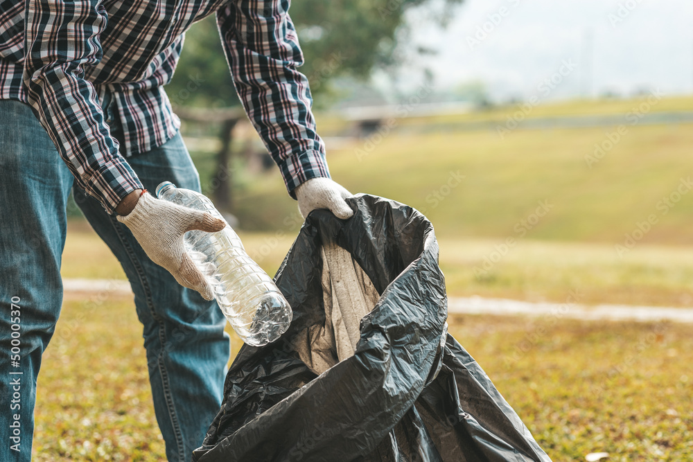 Φωτογραφία A man is picking up trash in a park, not throwing trash in the trash can ruin the beauty of the garden area and also cause global warming and harm animals