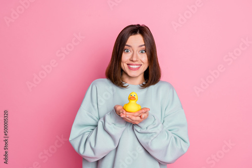 Photo of young adorable girl good mood hold hands little yellow duck playful isolated over pink color background © deagreez