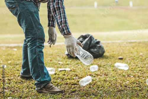 A man is picking up trash in a park, not throwing trash in the trash can ruin the beauty of the garden area and also cause global warming and harm animals. Concept of cleanliness in public areas.