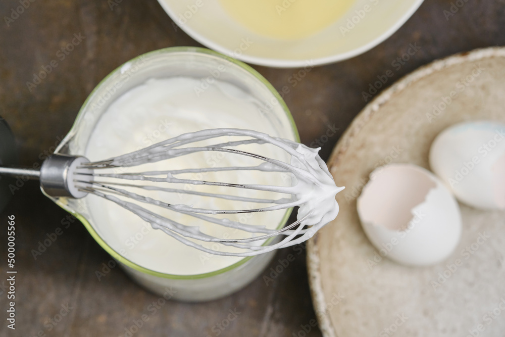 Process of cooking meringue, whipping egg whites to soft peaks in glass bowl with whisk. Whipping cream with a whisk. Shallow depth of field Process of cooking meringue, whipping egg whites to soft peaks in glass bowl with whisk. Whipping cream with a whisk. Shallow depth of field