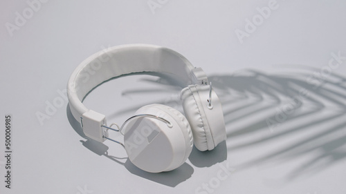 Headphones white with palm tree shadow. Summer day on a beach concept idea. Relax vacation on a sunny day