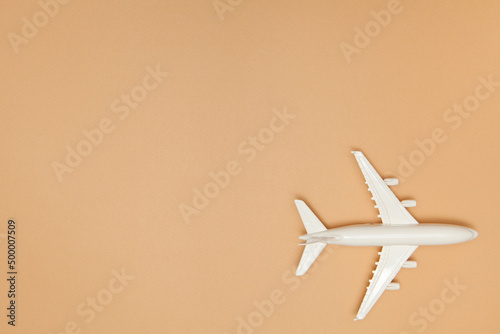 Airplane model. White plane on light brown background. Travel vacation concept. Summer background. Flat lay, top view, copy space.