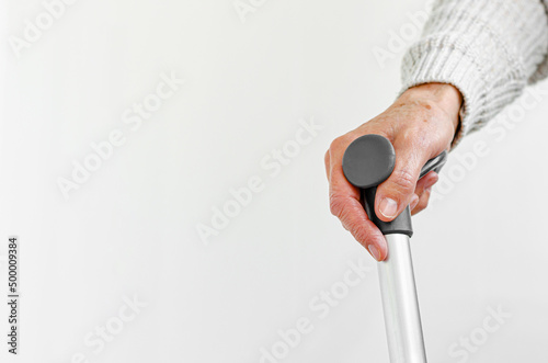 Retired woman holding metal walking stick in hand. Medical and healthcare concept. Copy space