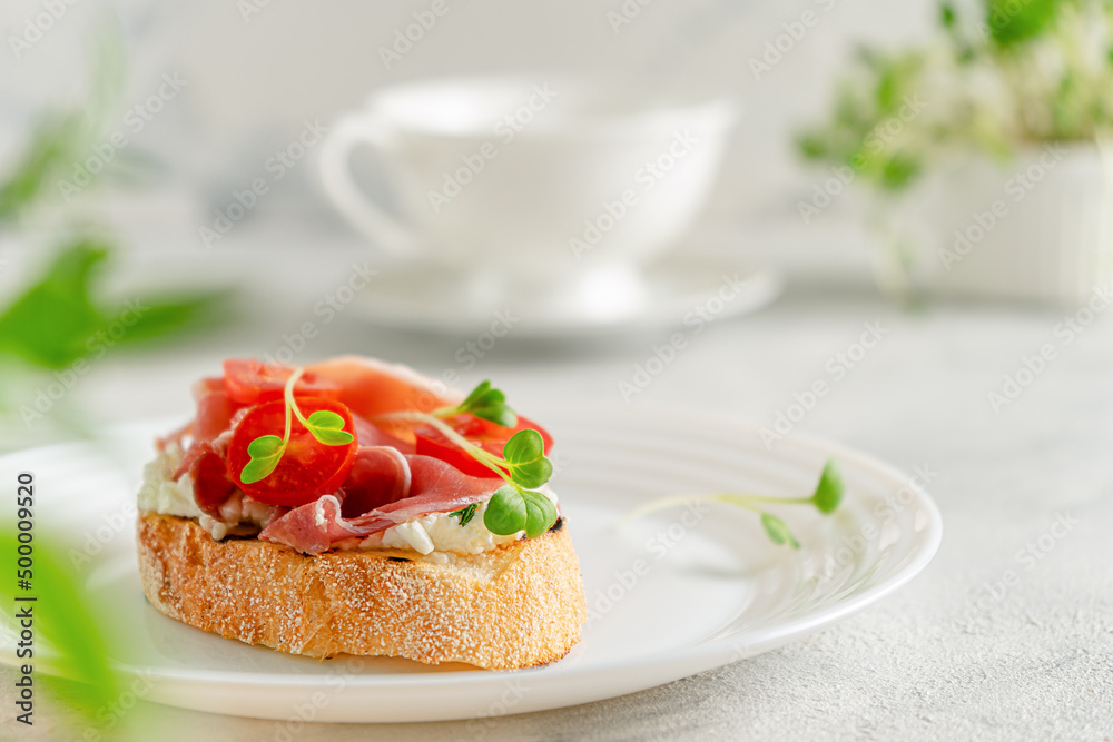 Ciabatta toast with prosciutto or jamon, tomato and soft cheese. Mediterranean breakfast. Copy space Ciabatta toast with prosciutto or jamon, tomato and soft cheese. Mediterranean breakfast. Copy space