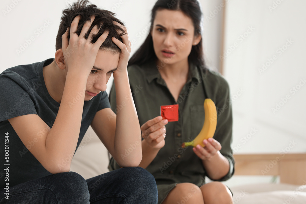Mother talking with her teenage son about contraception at home  