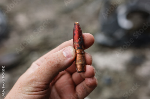 Close-up of human hand holding a large-caliber 12.7mm armor-piercing incendiary bullet photo