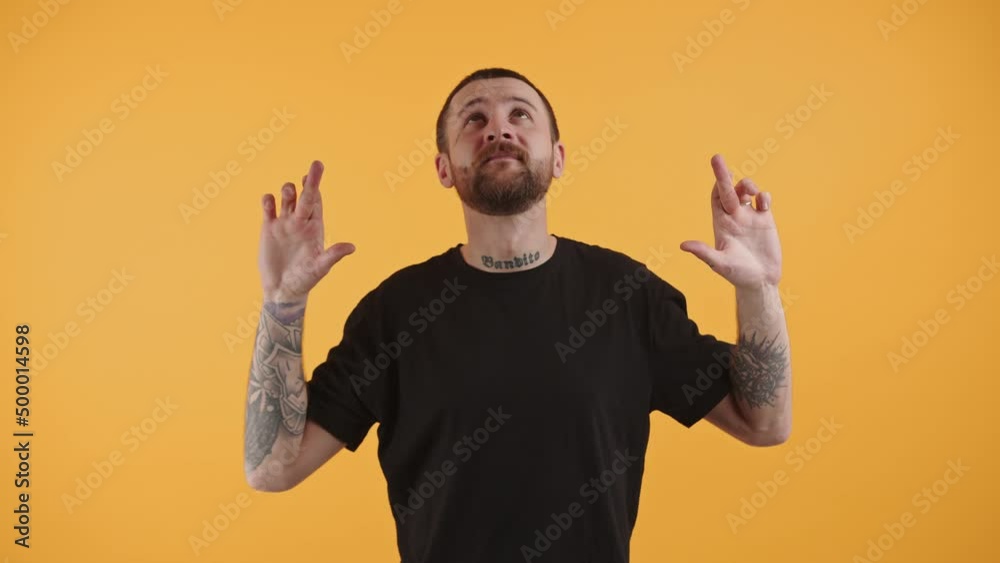 Bearded handsome man in a black t-shirt showing crossed fingers and looking on the top. High quality 4k footage Bearded handsome man in a black t-shirt showing crossed fingers and looking on the top. High quality 4k footage