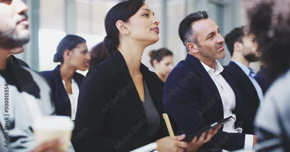  Businesswoman using a digital tablet  while sitting in a conference meeting.  Beautiful business woman using her device while sitting in a row with colleagues. Diverse coworkers in training. 