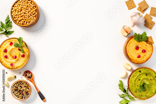 Colorful hummus served with bread snacks and herbs, flat lay