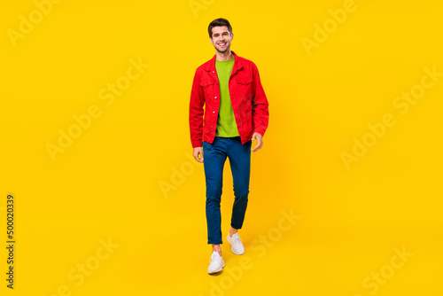 Full size photo of cute brunet young guy go wear shirt trousers sneakers isolated on yellow background