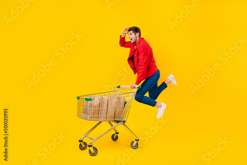 Obraz na plátne Full length body size view of attractive cheerful guy jumping carrying cart look