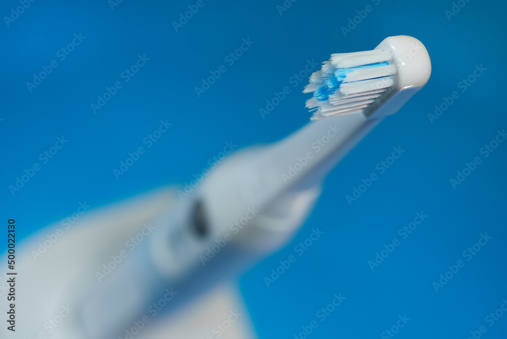 Electric ultrasonic toothbrush on blue background.