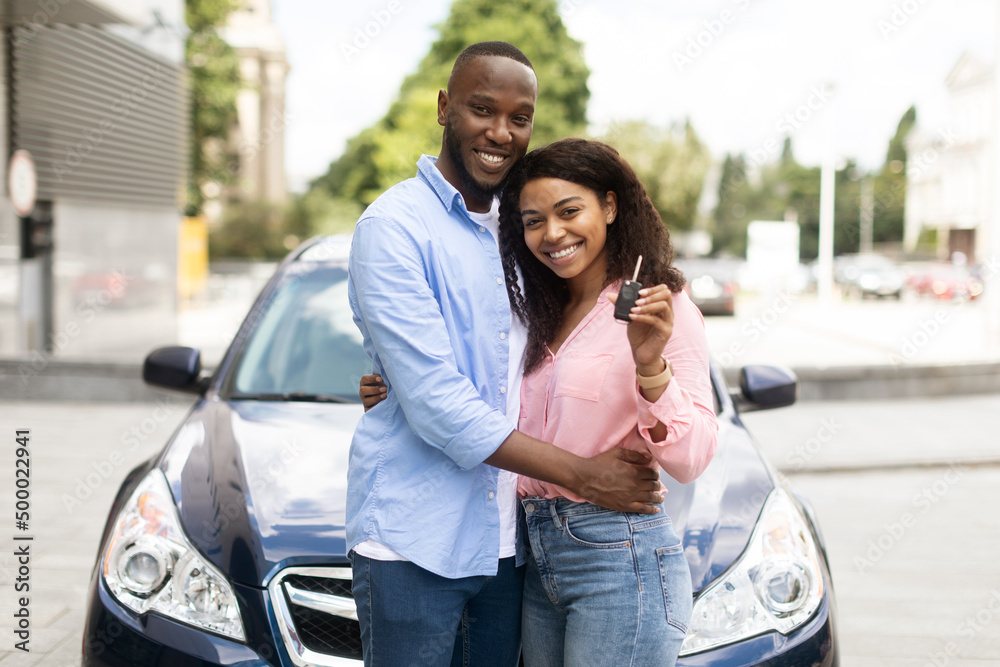 Happy black couple standing near car showing auto keys Happy black couple standing near car showing auto keys