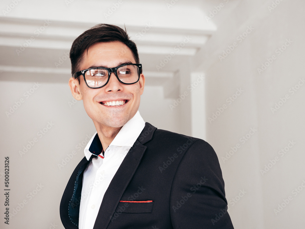 Portrait of handsome smiling model. Sexy stylish man dressed in is blue suit. Fashion hipster male posing near in white interior in studio. In spectacles or eyeglasses Portrait of handsome smiling model. Sexy stylish man dressed in is blue suit. Fashion hipster male posing near in white interior in studio. In spectacles or eyeglasses
