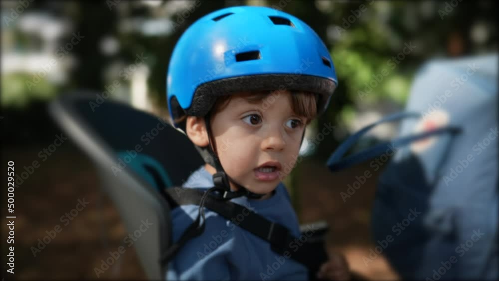 Child wearing helmet in bicycle back seat riding bike with parent Child wearing helmet in bicycle back seat riding bike with parent