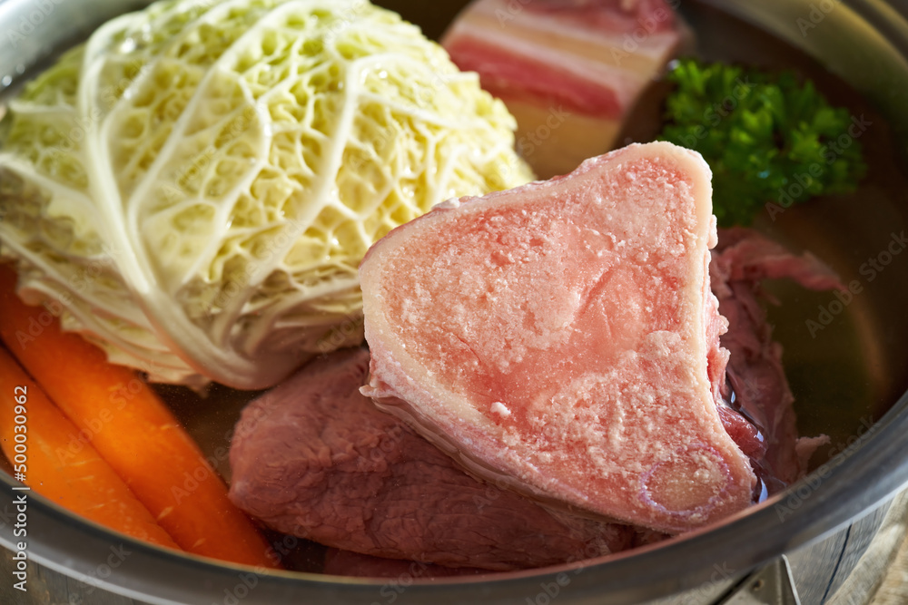 Ingredients for preparing beef bone broth - marrow bones and vegetables in a pot Ingredients for preparing beef bone broth - marrow bones and vegetables in a pot