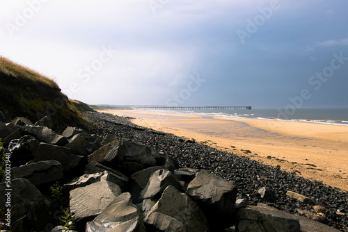 Black rocks and beach sand on stormy day at Hartlepool Headland, UK photo