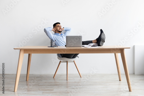 Wallpaper Mural Smiling Arab man leaning back sitting at desk Torontodigital.ca