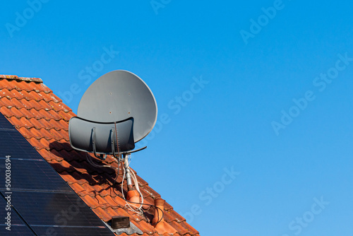 Slika na platnu Satellite dish on the roof of a house covered with terracotta tiles