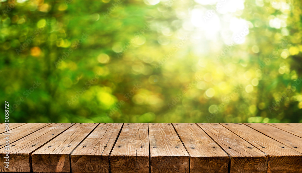 Empty old wooden table with fresh green spring theme in background Empty old wooden table with fresh green spring theme in background