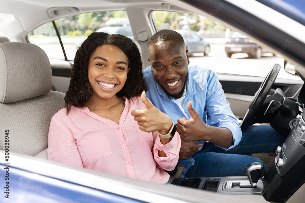 Happy black couple sitting in car gesturing thumbs up Happy black couple sitting in car gesturing thumbs up