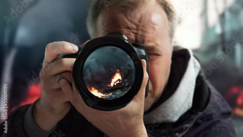 A journalist at war. A professional photojournalist shooting a report about a war, a terrorist attack or a man-made disaster in the middle of burning buildings at the risk of life