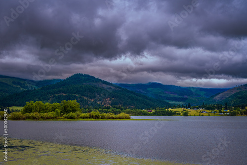 COUER D'ALENE RIVER WITH A MOUNTAIN RIDGE AND DARK CLOUDS photo