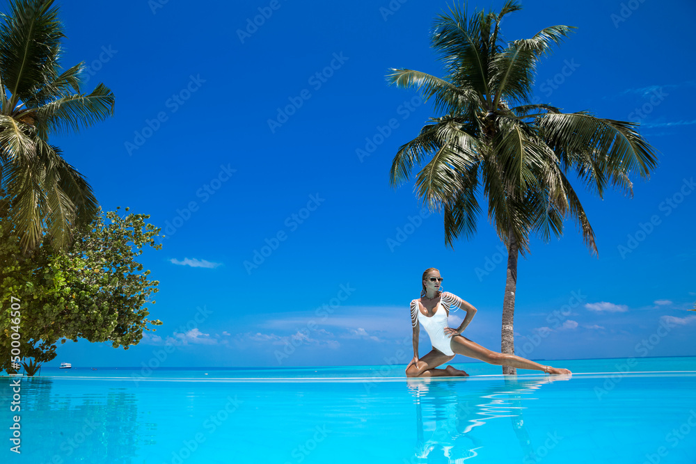 Elegant woman in white swimsuit in pool on tropical Maldives island. Beautiful bikini body girl in pool with view on horizon. Elegant model near the pool on beautiful Indian ocean landscape. Travel Elegant woman in white swimsuit in pool on tropical Maldives island. Beautiful bikini body girl in pool with view on horizon. Elegant model near the pool on beautiful Indian ocean landscape. Travel