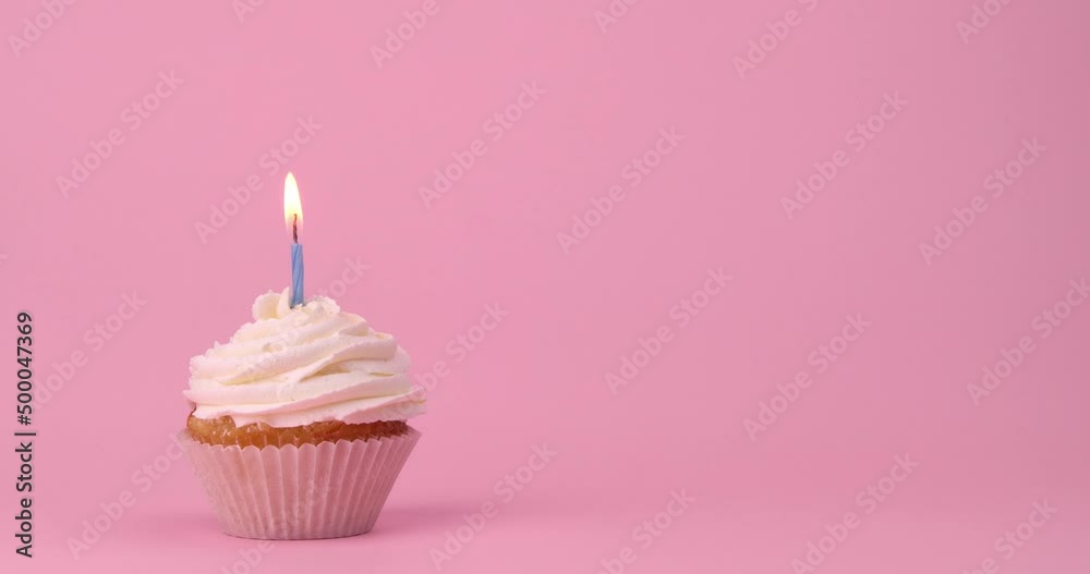Tasty birthday cupcake with burning candle on pink background Tasty birthday cupcake with burning candle on pink background