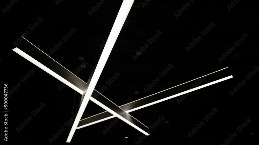 Low angle shot of glowing intersecting linear lights in the darkness - obrazy, fototapety, plakaty 