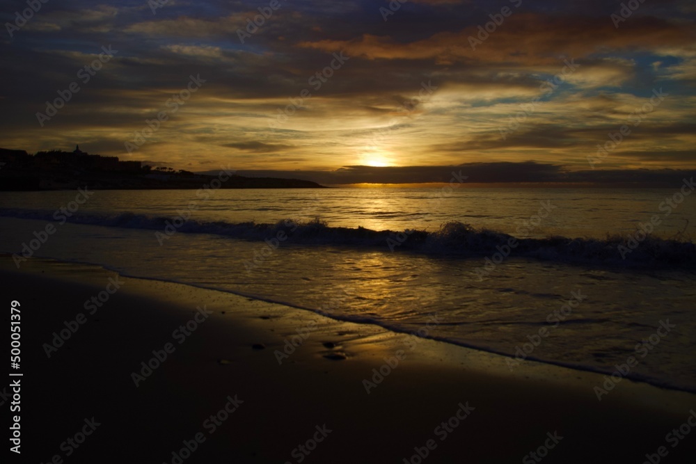 Golden sunset on the beach with splashing waves