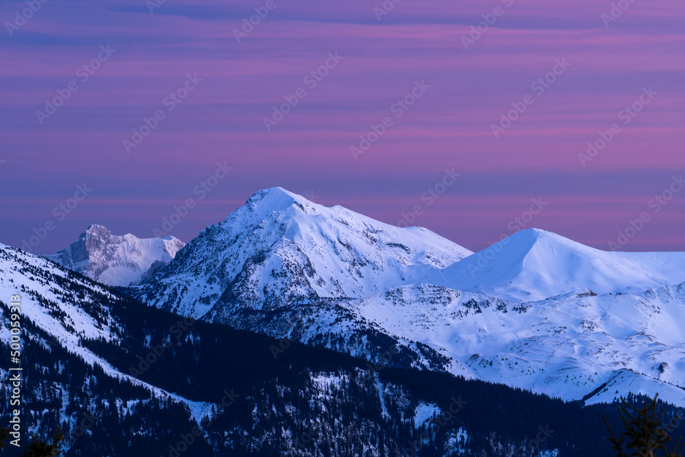 Sunset on snow covered mountains, with red and pink clouds