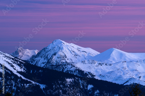 Sunset on snow covered mountains, with red and pink clouds