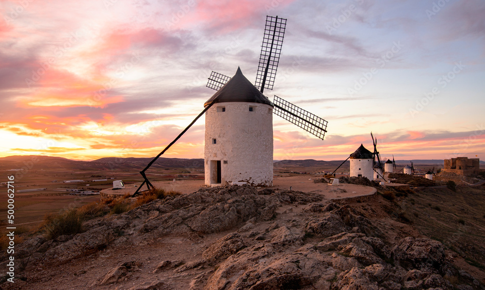 Old windmills at sunset in Castilla la Mancha, Spain, touristic place for Cervantes' novel, Don Quixote - obrazy, fototapety, plakaty 