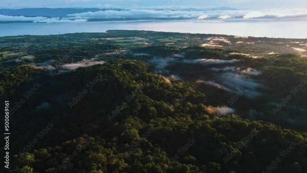 aerial panoramic of tropical landscape and steep mountain lit by sunset