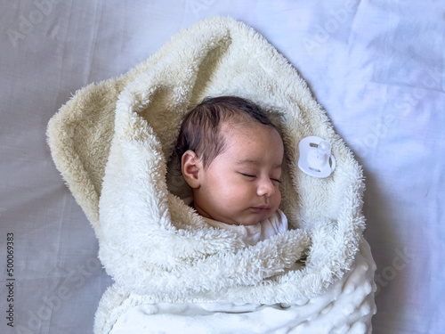 Sweet peaceful baby lying on a white bedsheet enjoy daytime photo