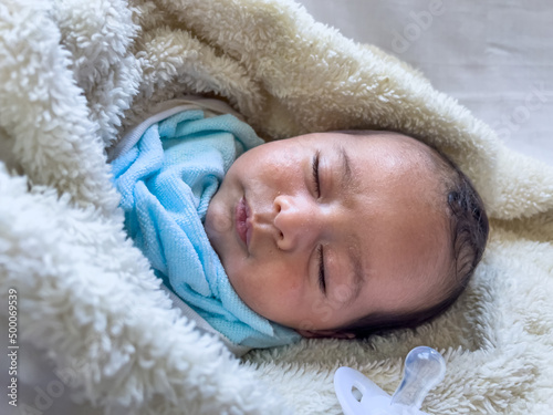 Sweet peaceful baby lying on a white bedsheet enjoy daytime photo