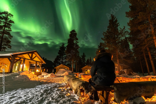 Northern Lights in the arctic winter with snow and chalets