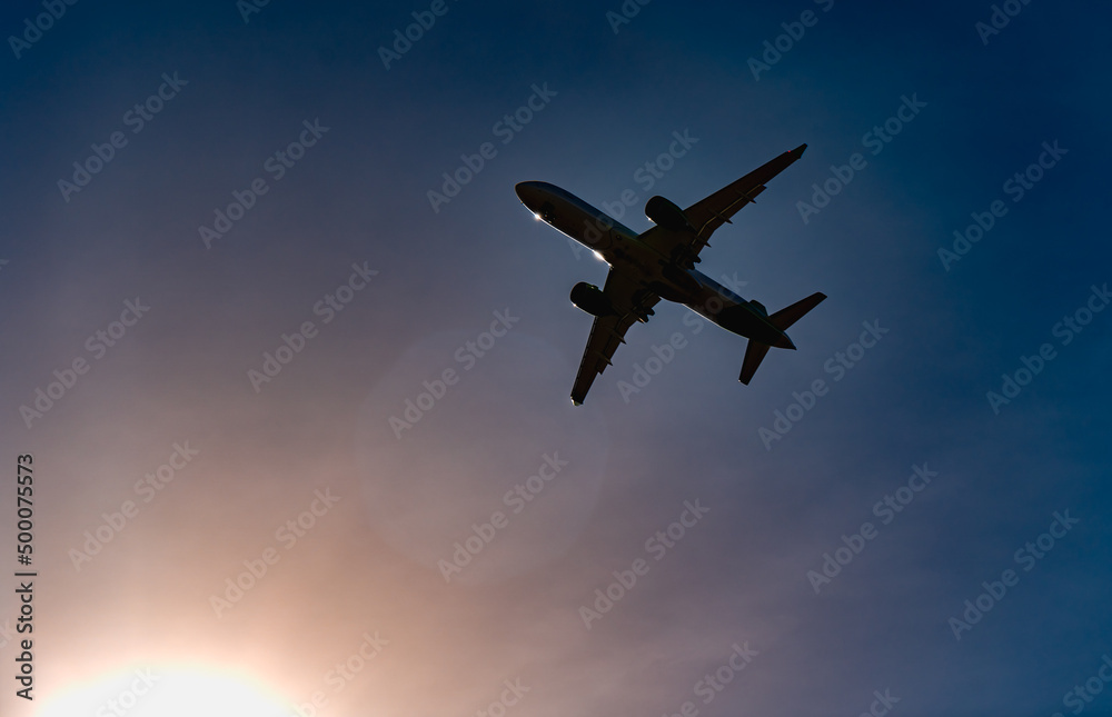 Passenger airplane. View exactly from below, silhouette against the blue sky and sunset. Plane taking off Passenger airplane. View exactly from below, silhouette against the blue sky and sunset. Plane taking off