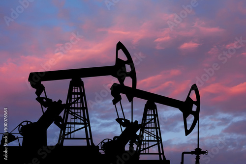 Pump- jacks on sunset background. Oil and gas production