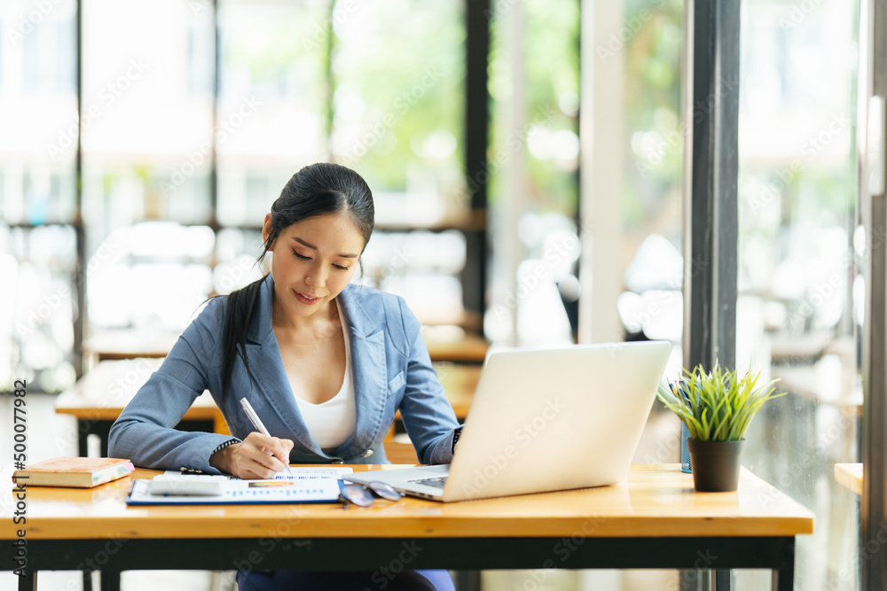 Portrait of Asian young female working on laptop and financial report at office. Portrait of Asian young female working on laptop and financial report at office.