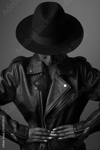 Vertical shot of styilish woman wearing hat and leather jacket. Black and white.