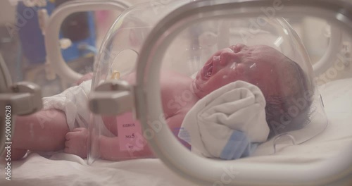Closeup little newborn baby infant sleeping and crying in incubators for newborns, Newborn baby having the the breathing problem after birth, newborn in NICU, Neonatal intensive care unit