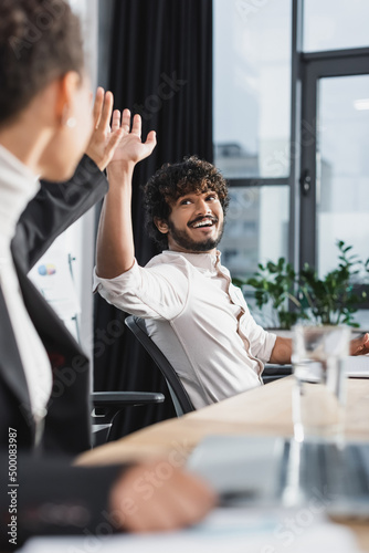 Positive indian businessman giving high five to african american colleague in office. photo