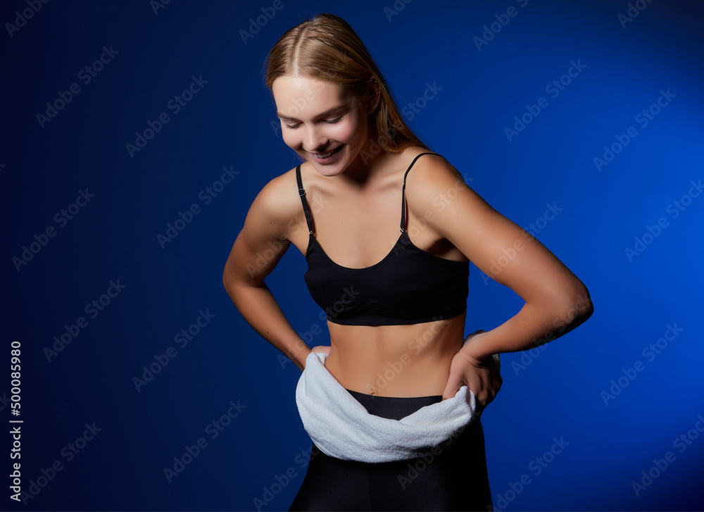 young fair-haired girl with a towel in a fitness studio. closeup photo. dark background young fair-haired girl with a towel in a fitness studio. closeup photo. dark background